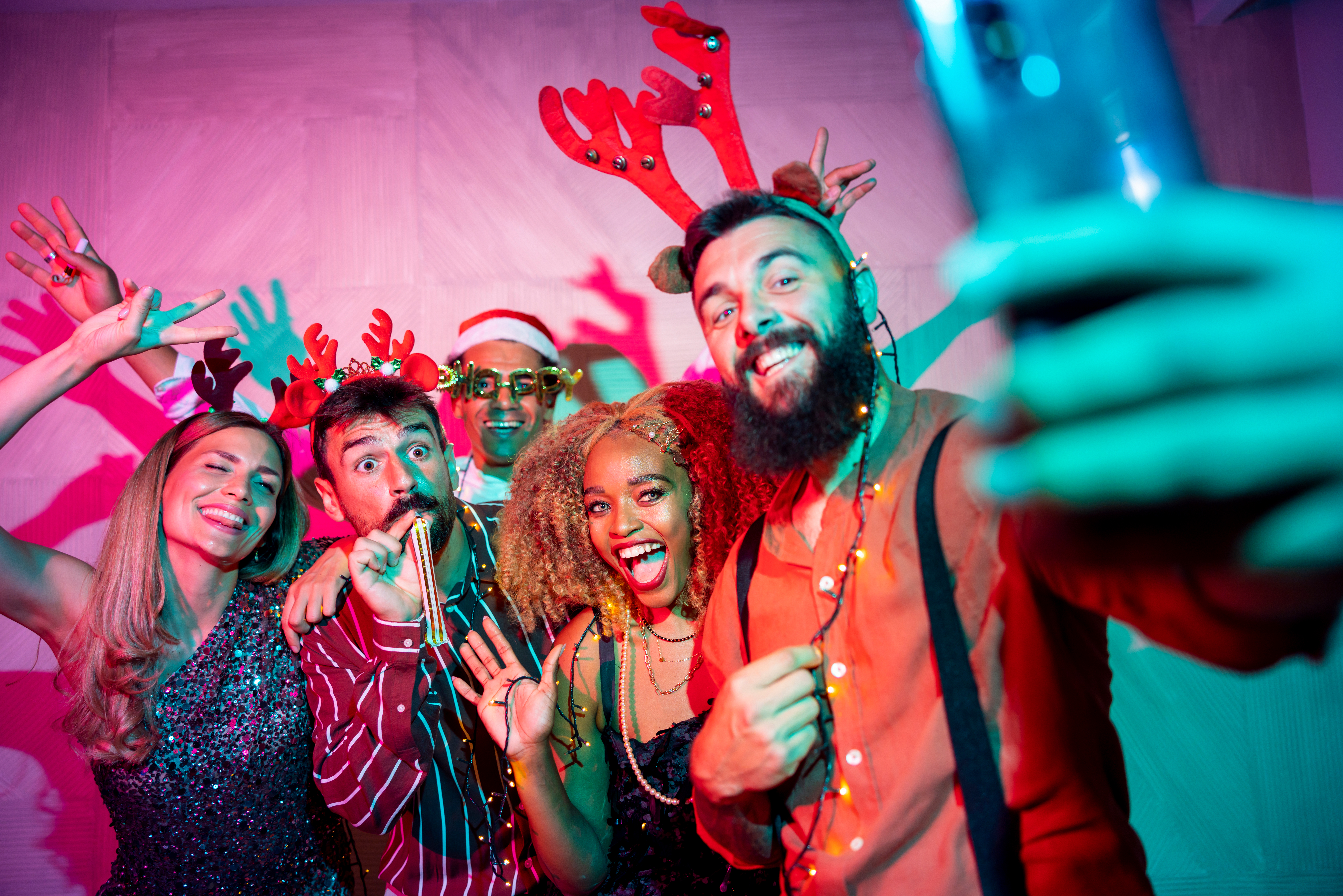 Group of cheerful young friends having fun taking selfies at New Year Eve party